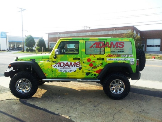 a car is wraped in graphics for adams of annapolis