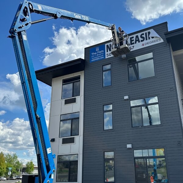 An image of the installation of an apartment building's Now Leasing banner.