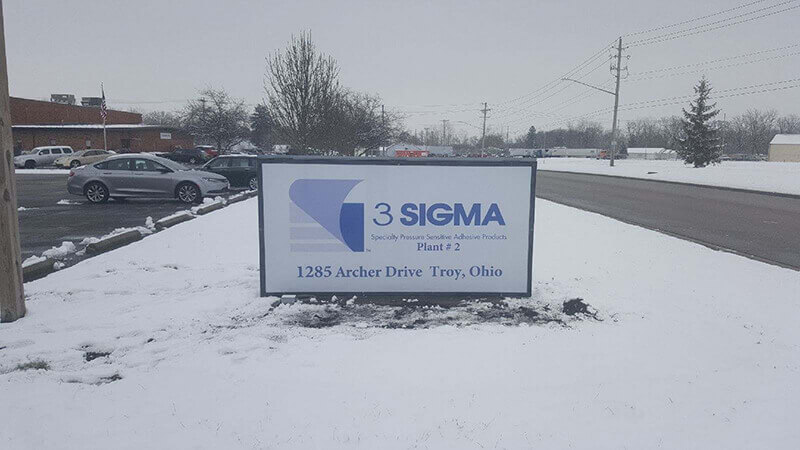 Sigma Exterior Signage on the snow with cars on the parking lot 