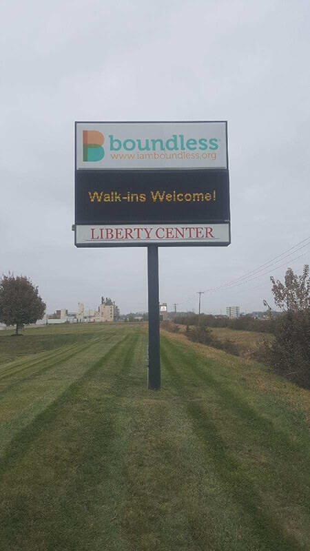 Boundless signage on the middle of the field with trees on the side