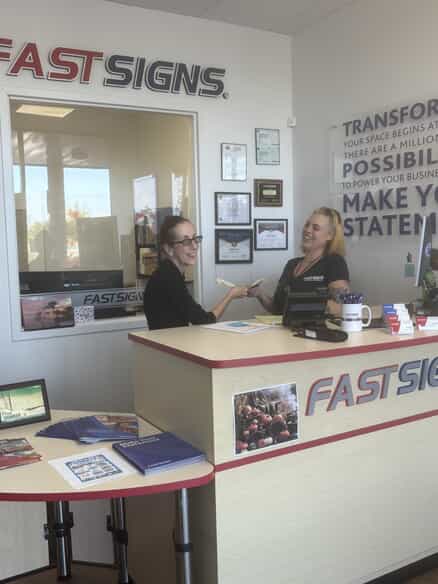 An image of two FASTSIGNS employees behind the counter.