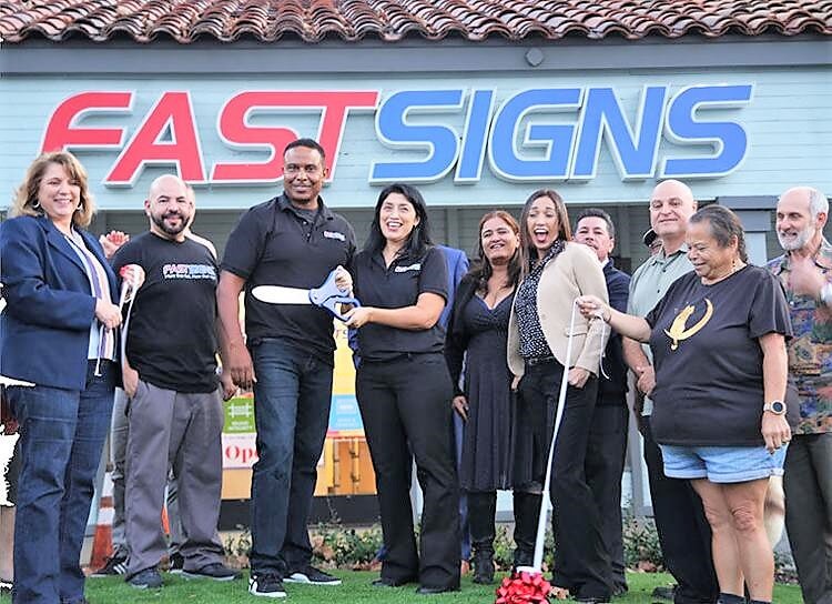 Husband and wife team, center, André Richardson and Norma Ochoa are pictured here during the grand opening of their business, FASTSIGNS.