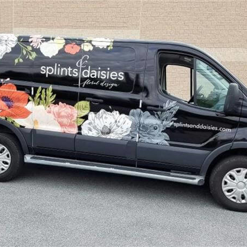 Black van with custom floral vehicle graphics
