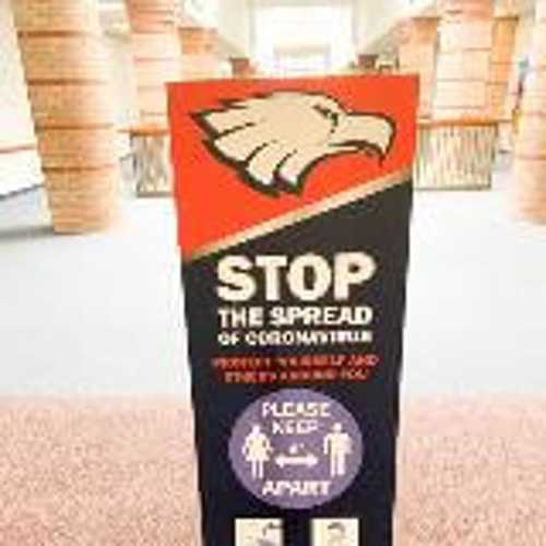 COVID awareness frame signage on the side of the school hallway